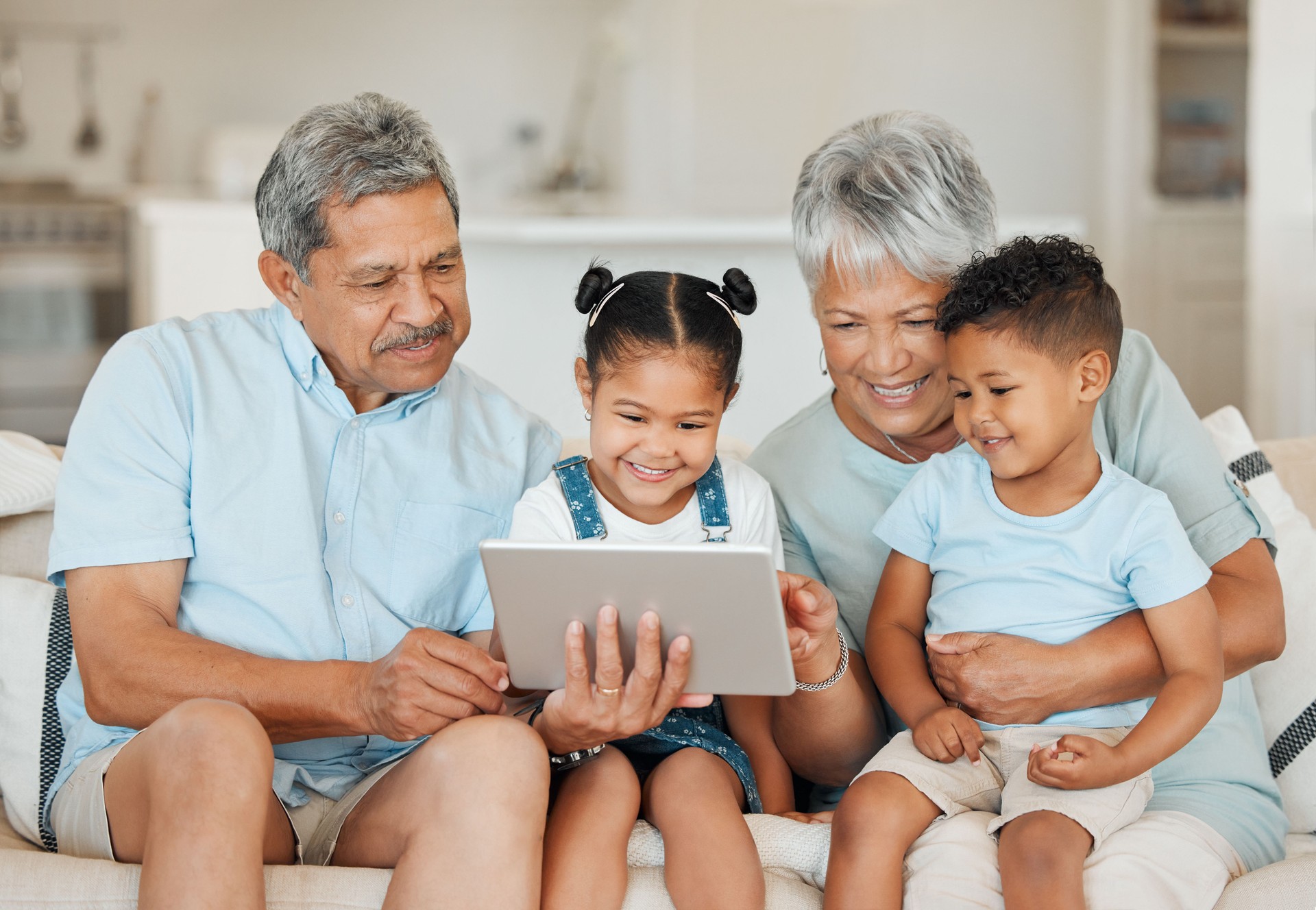 Shot of grandparents bonding with their grandchildren and using a digital tablet on a sofa at home